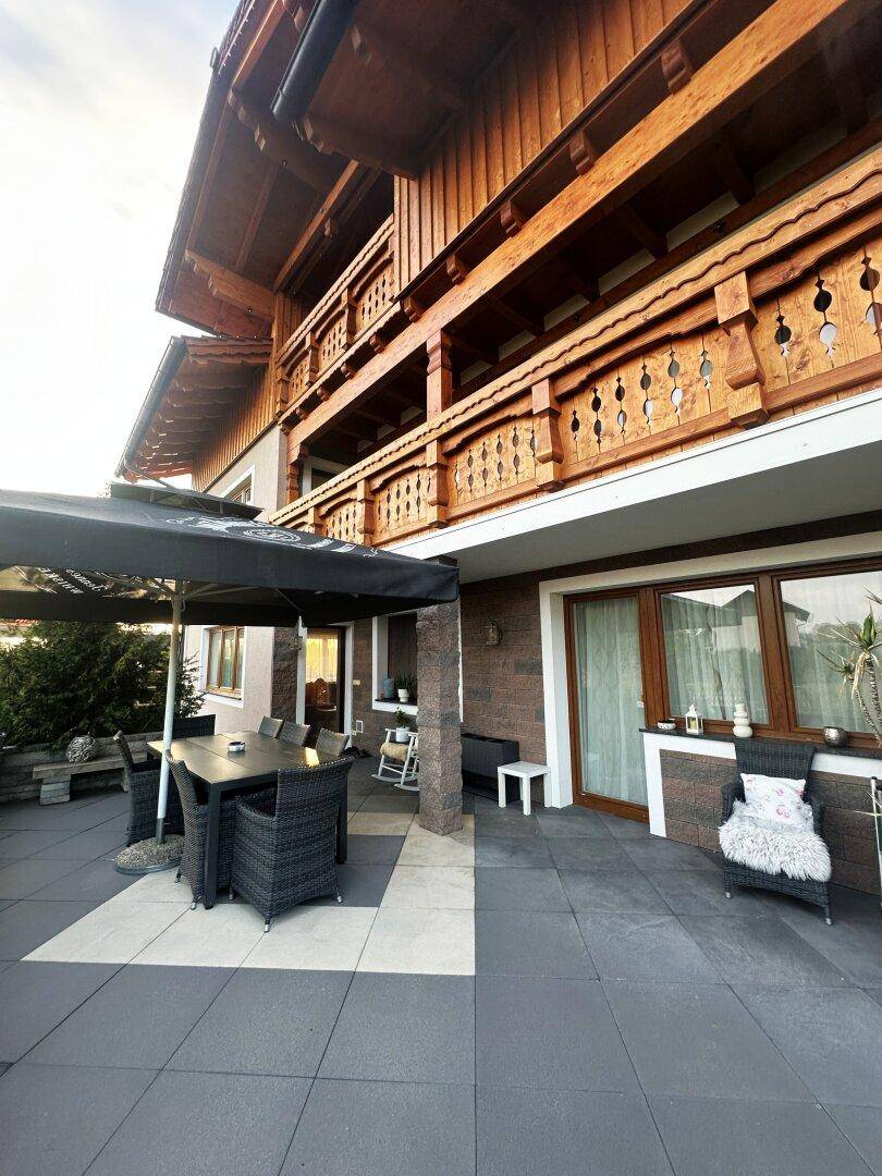 Geräumige Terrasse mit modernen Outdoor-Möbeln und großem Sonnenschirm, angrenzend an das Haus.