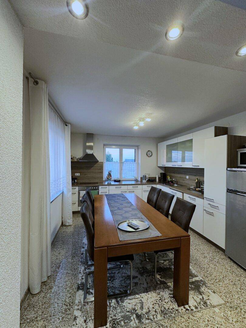 Geräumige Küche mit Essbereich, weißen Schränken und modernen Geräten, ideal für Familien.