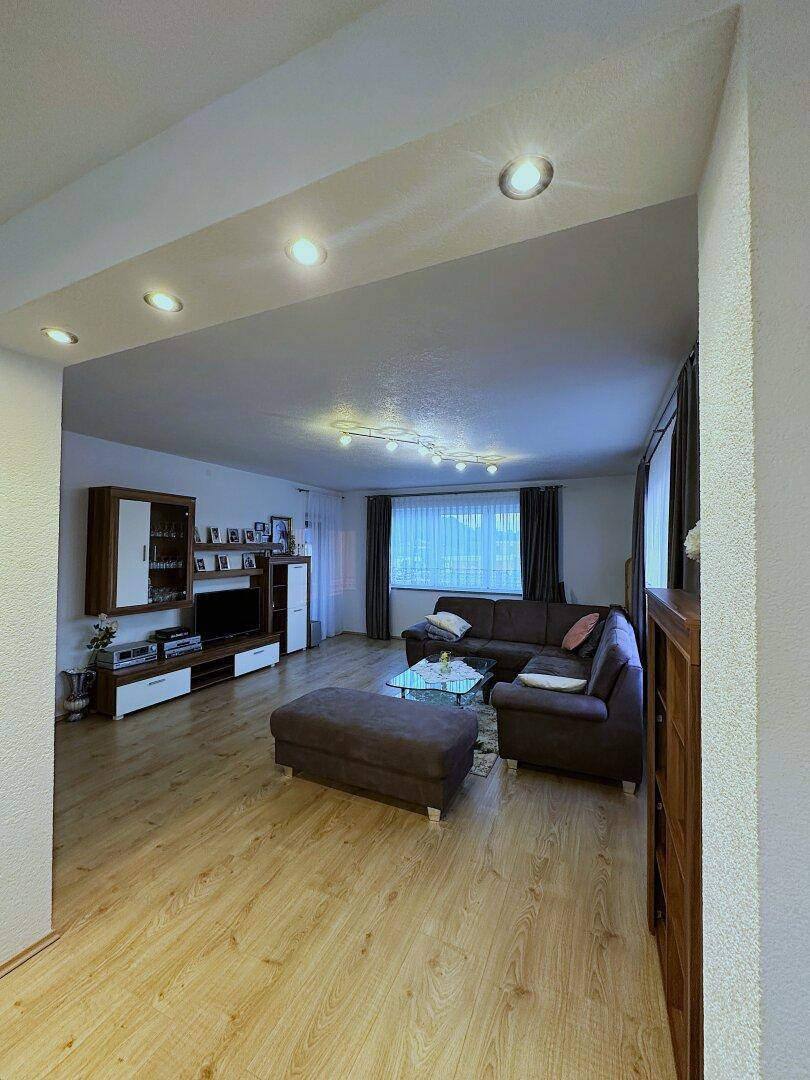 Gemütliches Wohnzimmer mit großem Ecksofa, Laminatboden und moderner Unterhaltungselektronik.