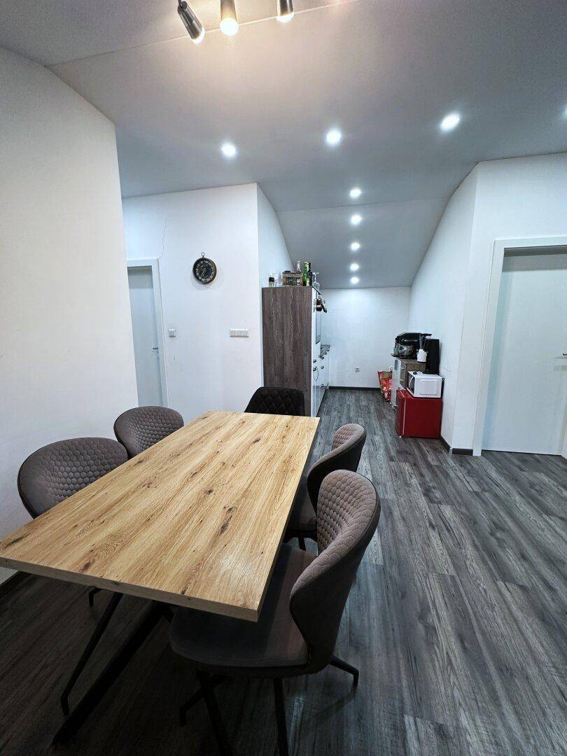 Essbereich im Dachgeschoss mit Holztisch und Stühlen, angrenzend an eine kleine Küchenzeile.