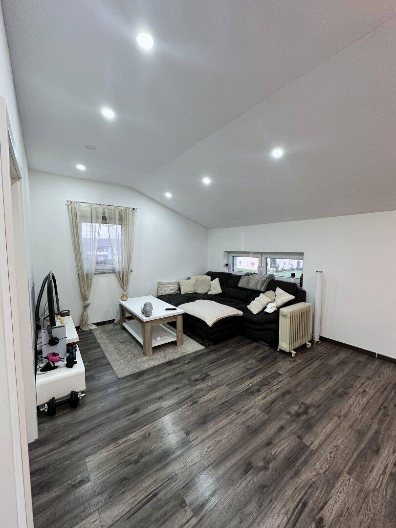 Helles Wohnzimmer im Dachgeschoss mit Schrägdach, modernem Laminatboden und gemütlicher Sitzecke.