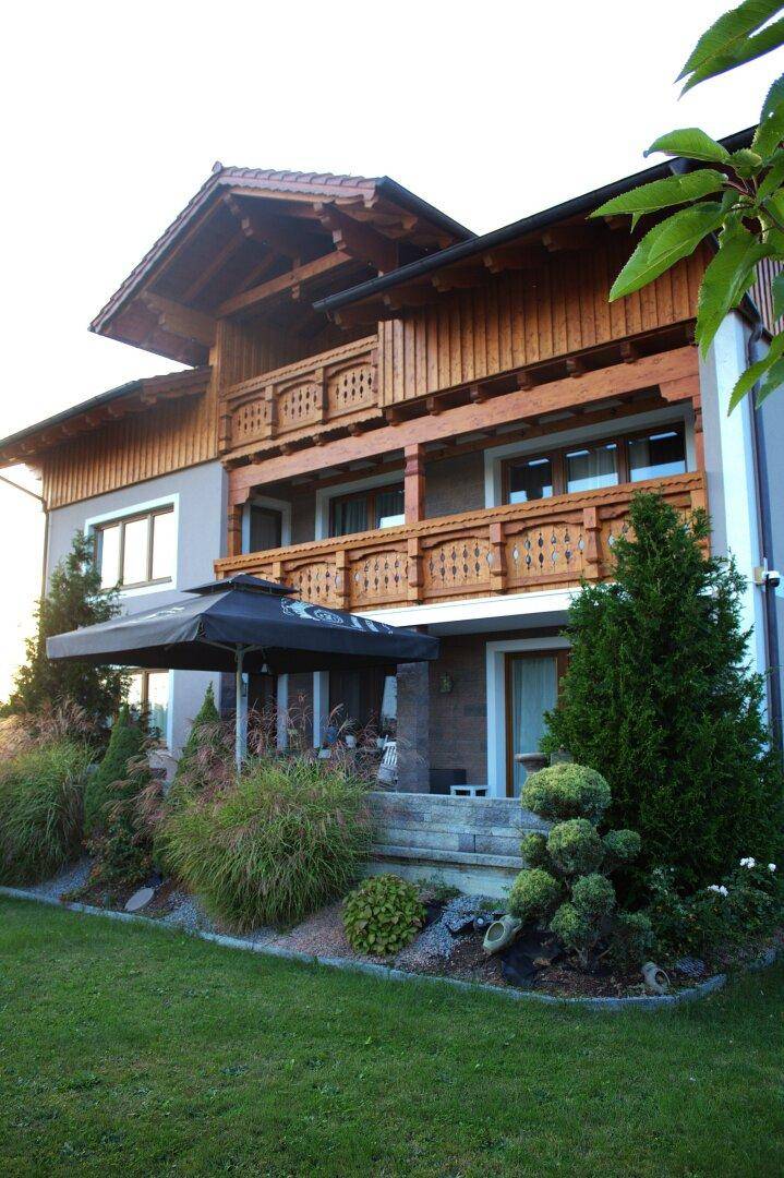 Ansicht des Hauses mit traditionellen Holzbalkonen und einem liebevoll gestalteten Gartenbereich.