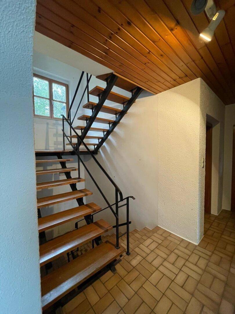 Flur mit Holztreppe, Fliesenboden und einer Holzdecke, die einen rustikalen Charme verleiht.