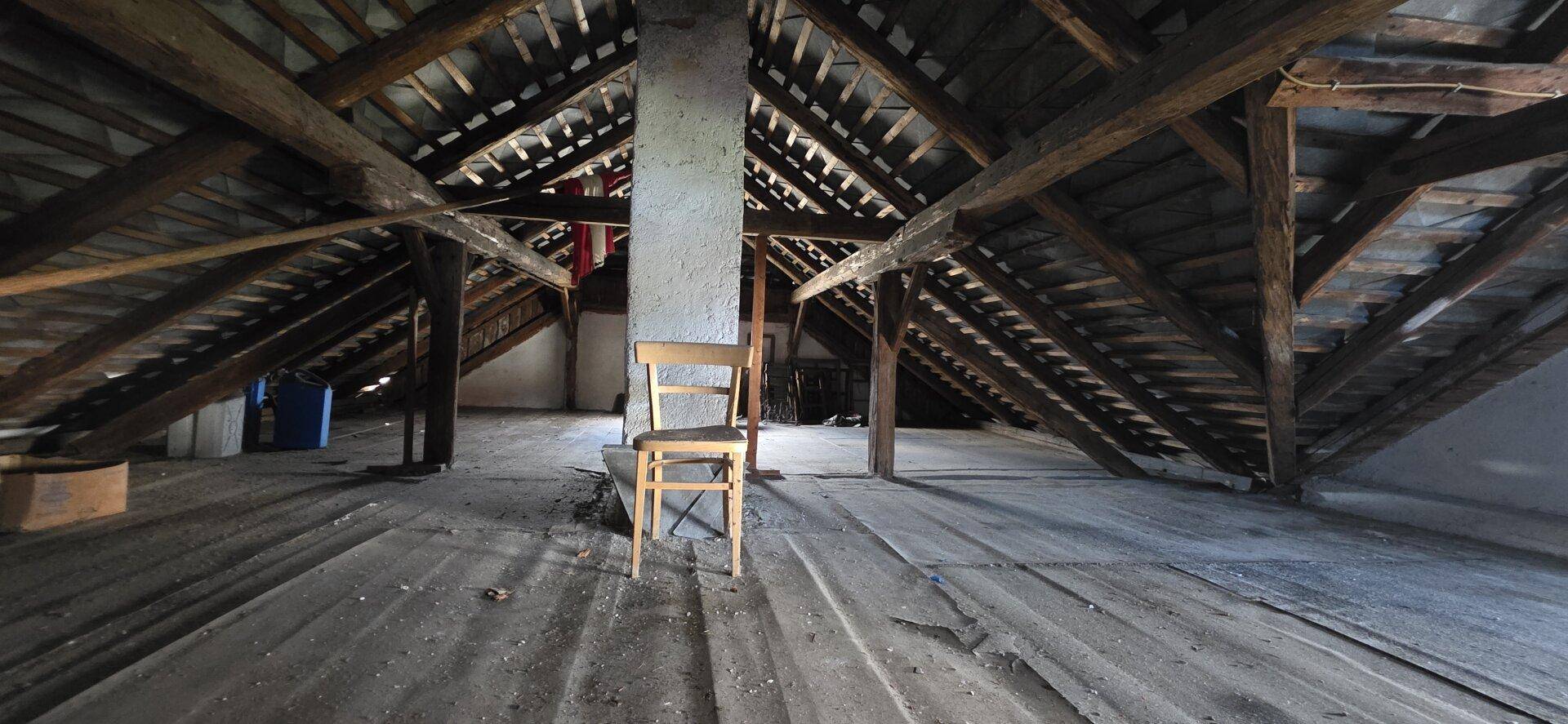 Großer Dachboden mit sichtbarer Holzkonstruktion und Holzdielenboden, bereit für Renovierung.
