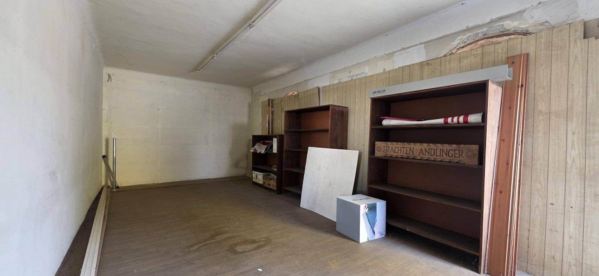 Geräumiger Abstellraum mit Regalen, Holzverkleidung und sichtbaren Gebrauchsspuren.