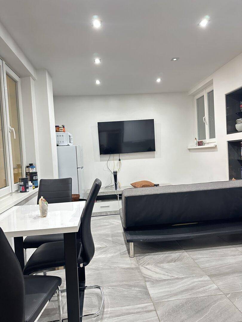 Offener Wohn- und Essbereich mit Esstisch, Sofa und Fernseher, angrenzend an die Küche.