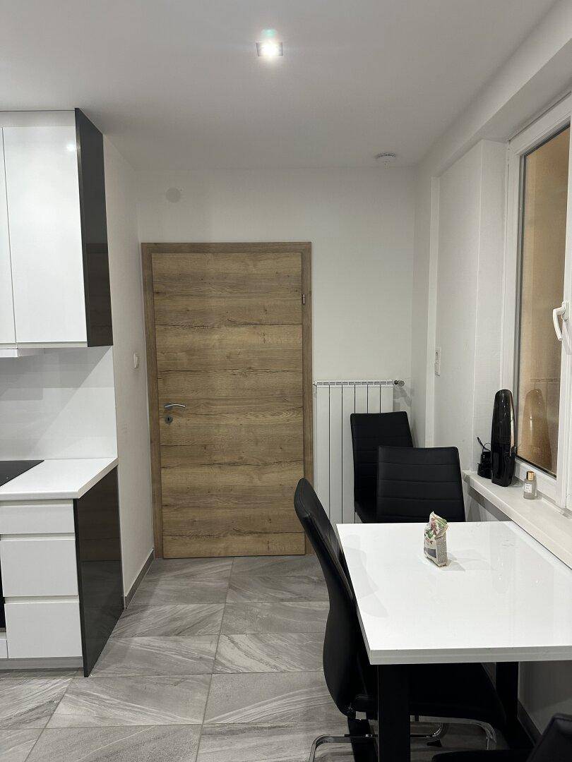 Essbereich mit modernem Tisch und Stühlen, Heizkörper unter dem Fenster und Holztür.