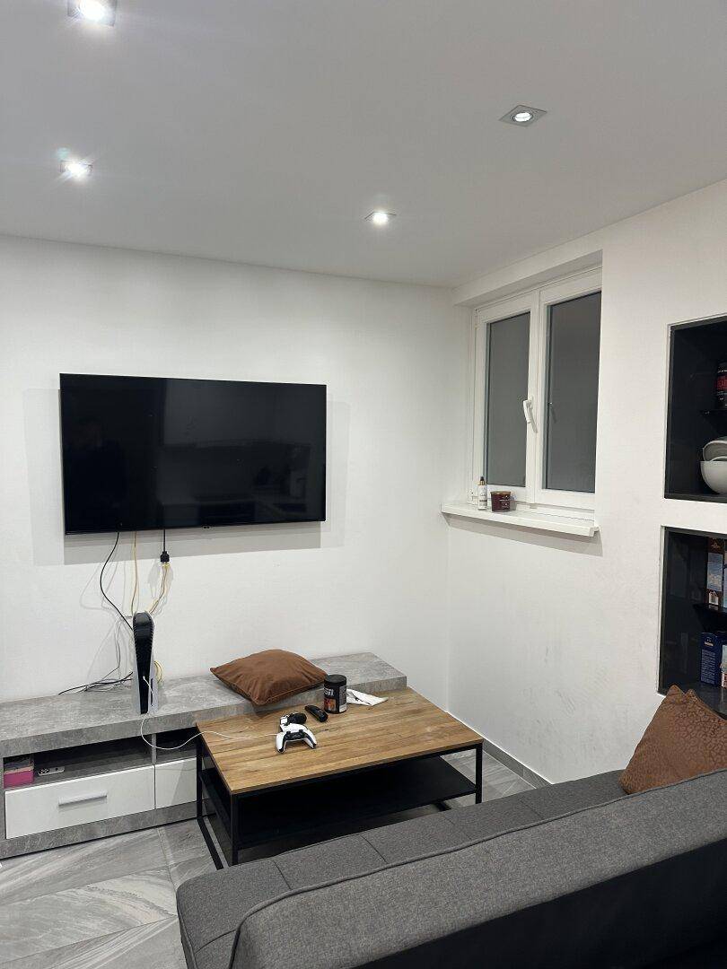 Gemütlicher Wohnbereich mit Sofa, Couchtisch und großem Fernseher an der Wand.