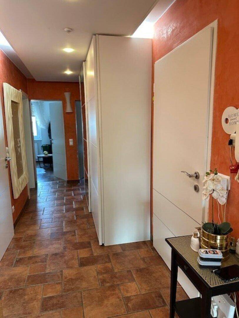 Heller Flur mit Terrakotta-Fliesen, weißen Türen und integrierten Schränken.