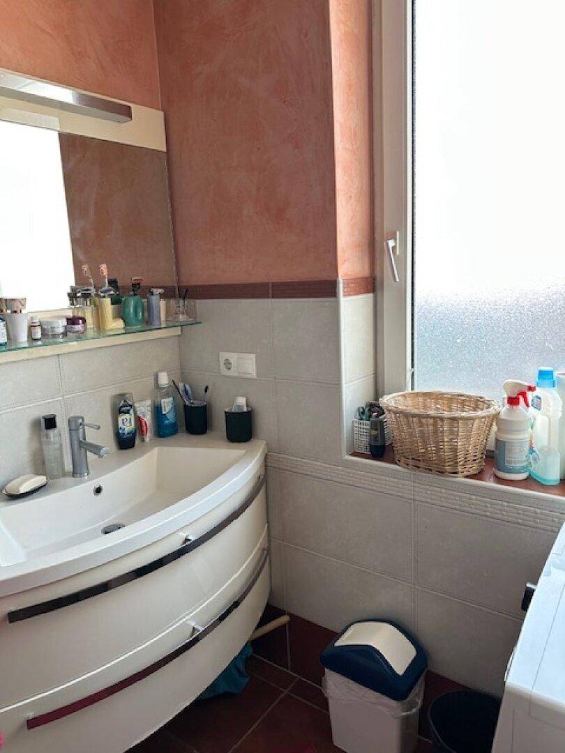 Badezimmer mit modernem Waschbecken, Spiegel und Fenster für Tageslicht.