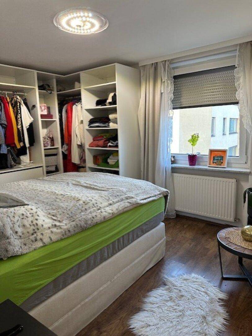 Schlafzimmer mit großem Bett, offenem Kleiderschrank und Holzboden.