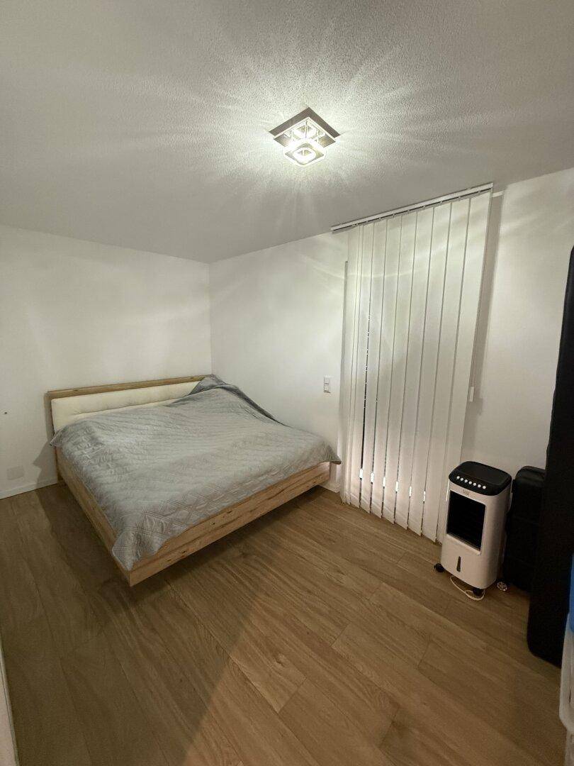 Helles Schlafzimmer mit Holzboden, Doppelbett und großem Fenster.