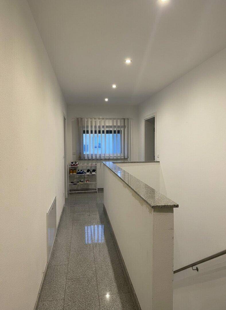 Heller Flur im Obergeschoss mit gefliestem Boden und Fenster.