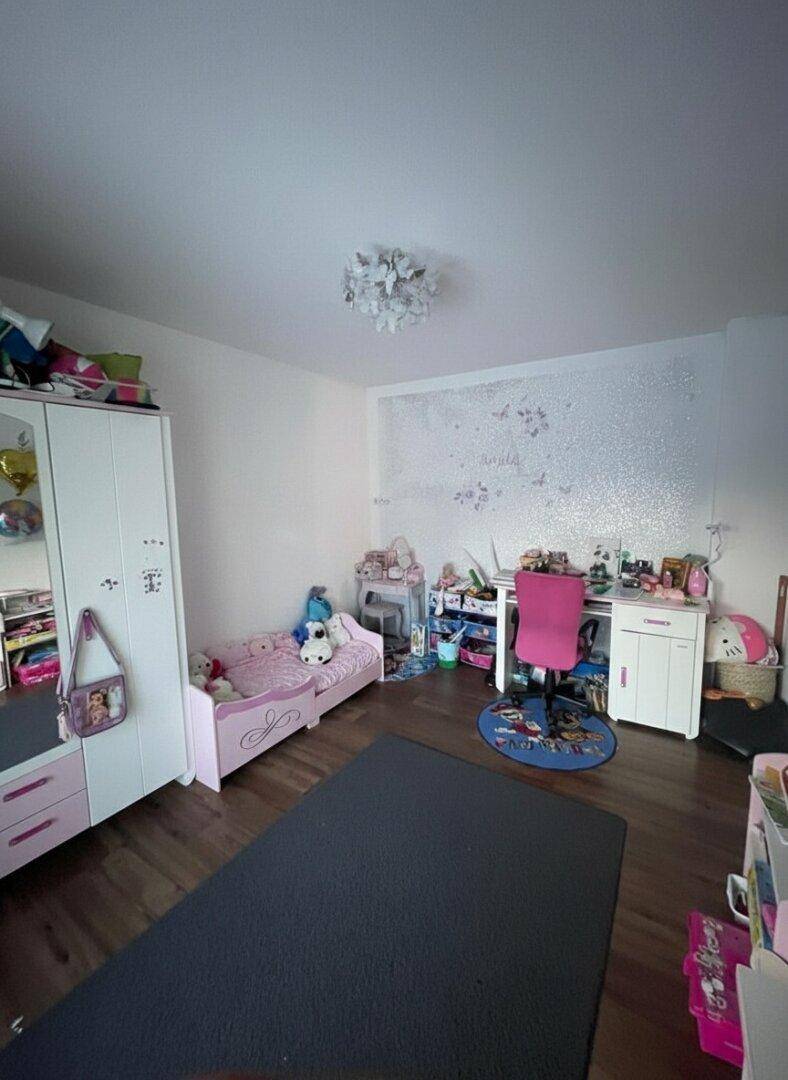 Kinderzimmer mit Holzboden, Einzelbett und verspielter Dekoration.