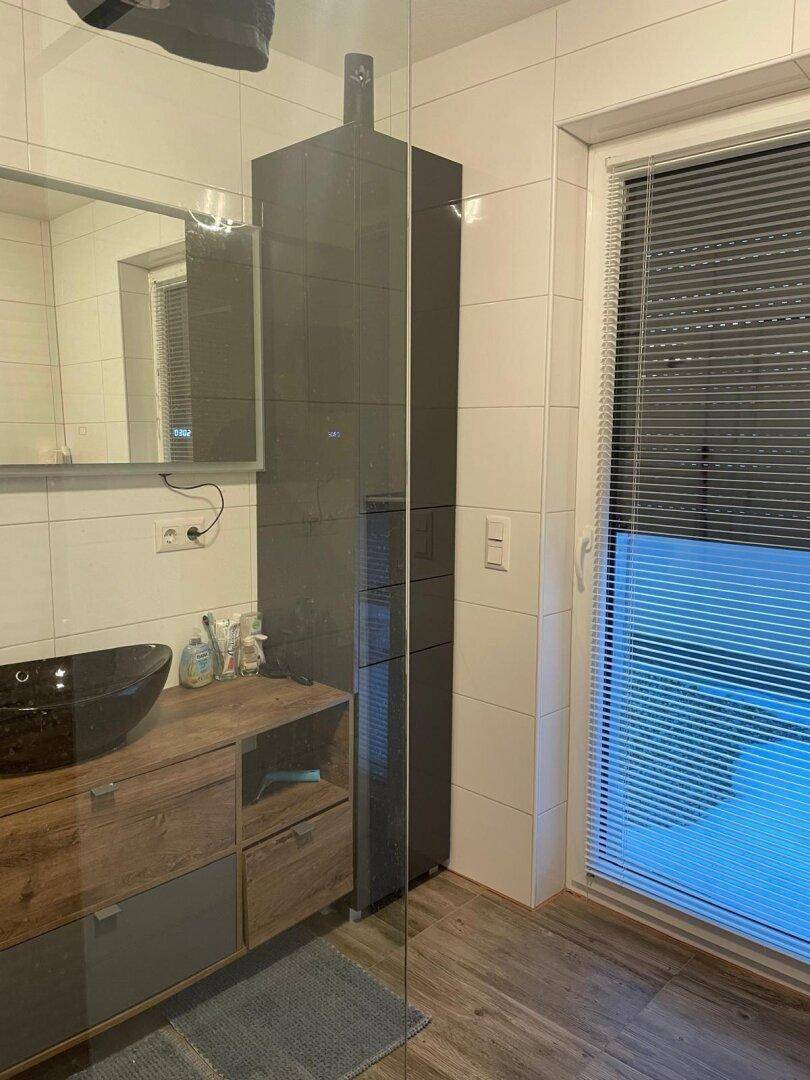 Modernes Badezimmer mit Waschbecken, Spiegel und ebenerdiger Dusche.