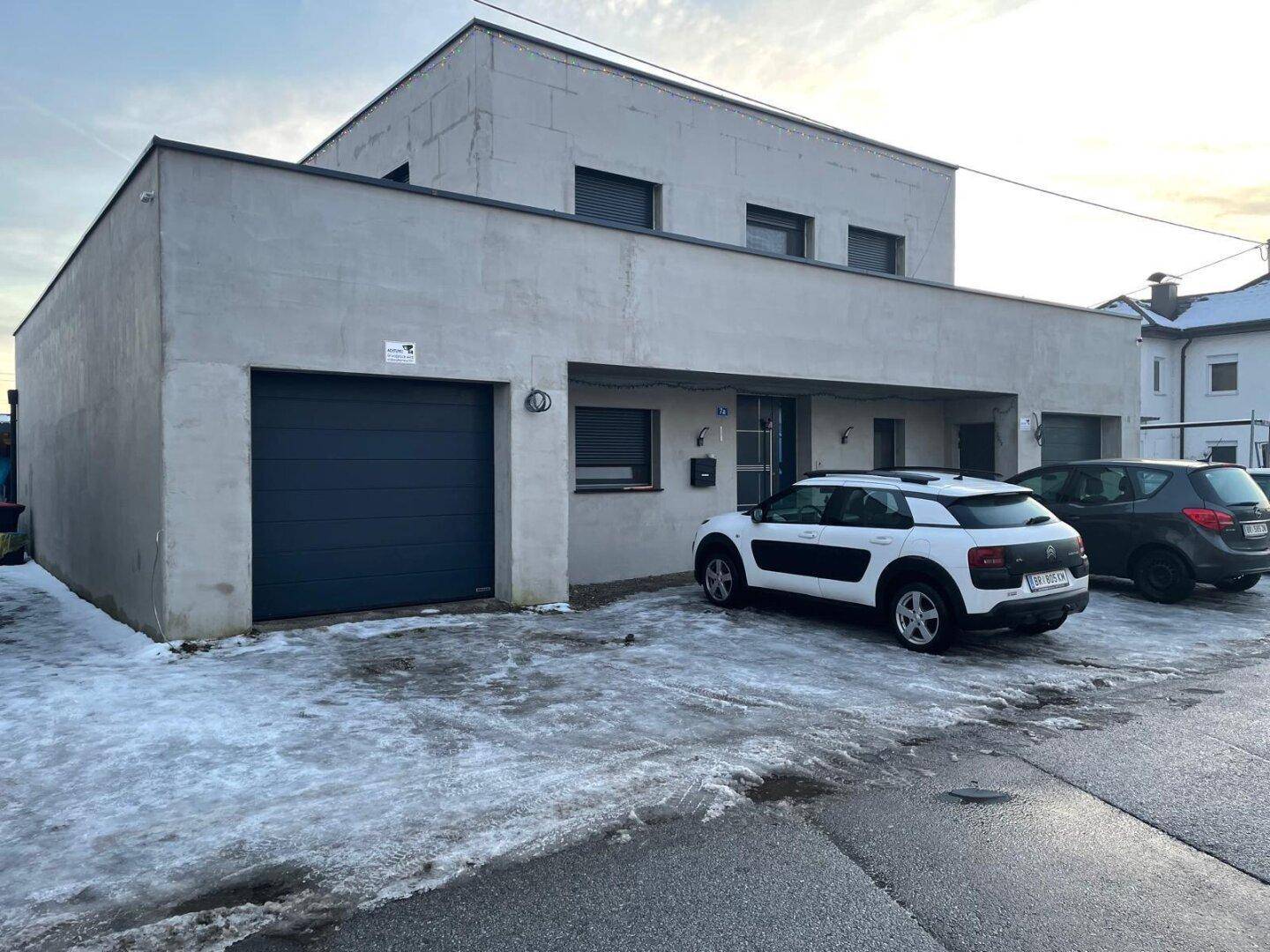 Modernes Einfamilienhaus mit Garage und Stellplätzen im Winter.