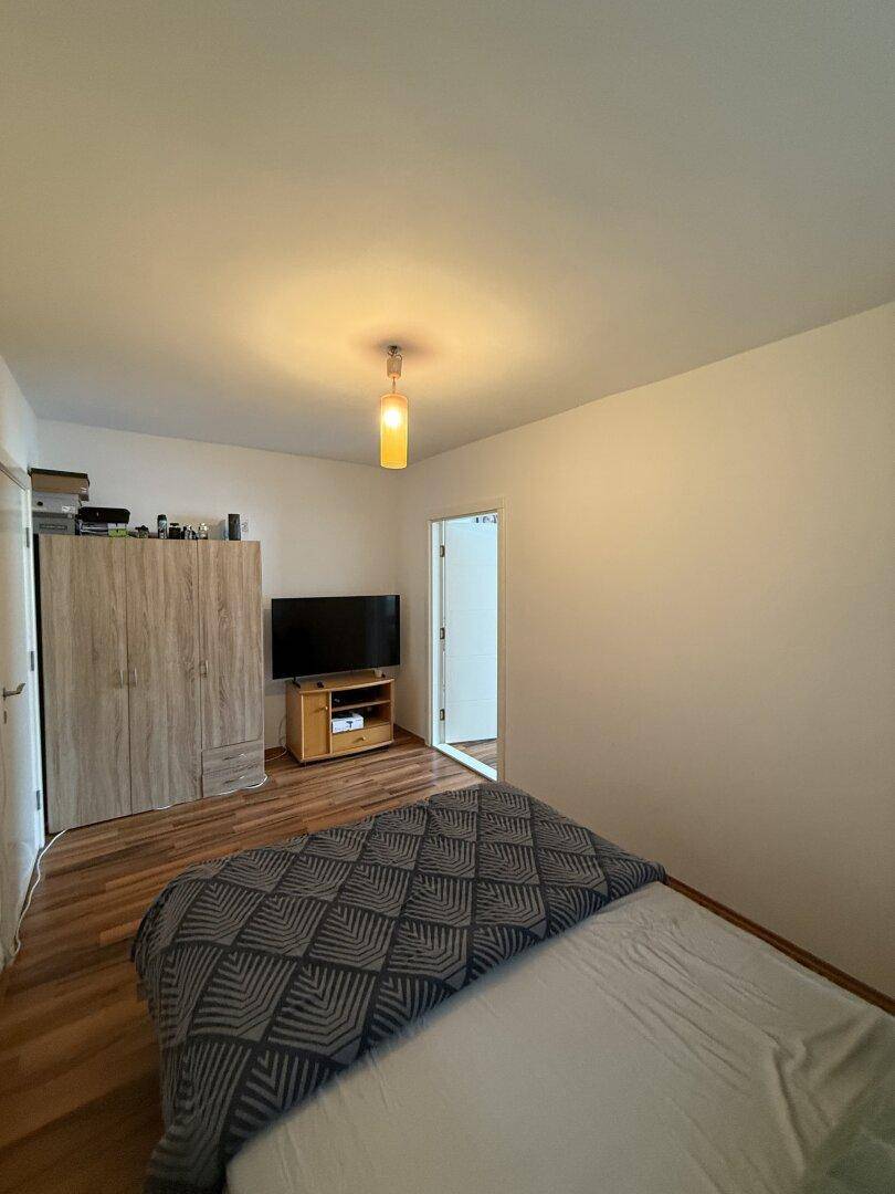 Schlafzimmer mit Laminatboden, Bett und einem Kleiderschrank, der viel Stauraum bietet.