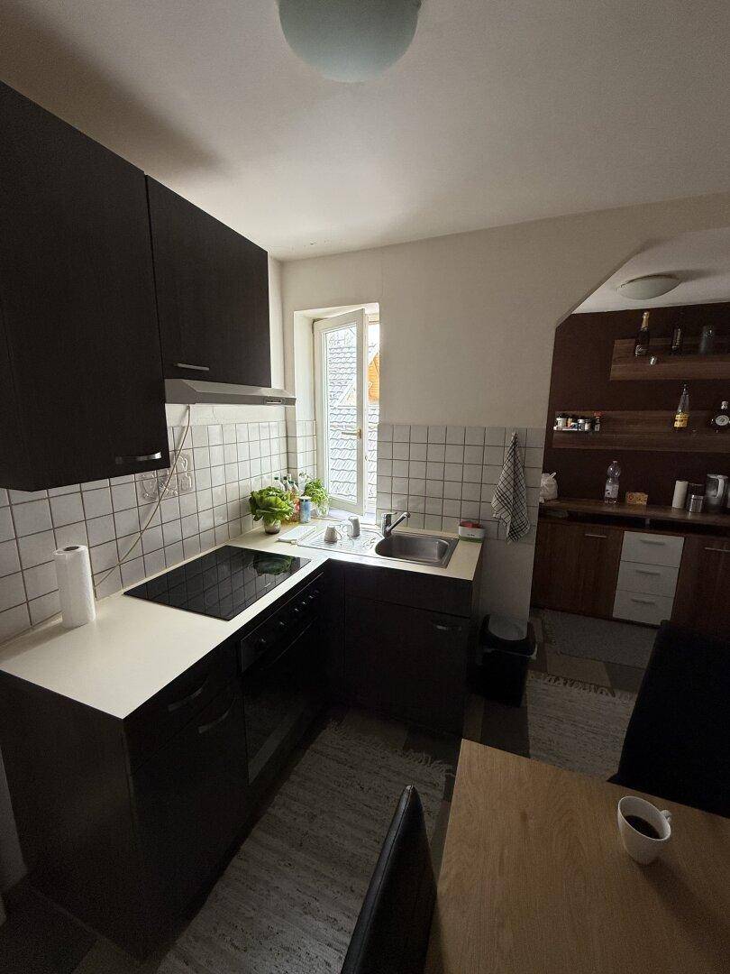 Moderne Küche mit dunklen Unterschränken, hellem Fliesenspiegel und einem Fenster mit Blick nach draußen.