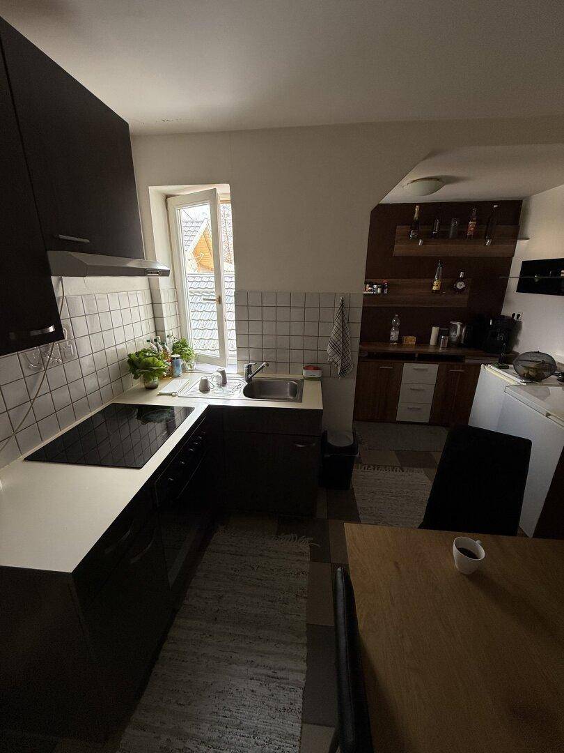 Praktische Küche mit dunklen Schränken, integriertem Kochfeld und einem Fenster für Tageslicht.