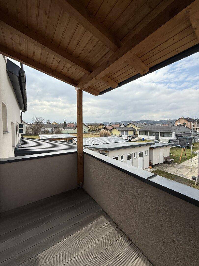 Geräumiger Balkon mit Holzdielen und einer Holzüberdachung, ideal zum Entspannen im Freien.