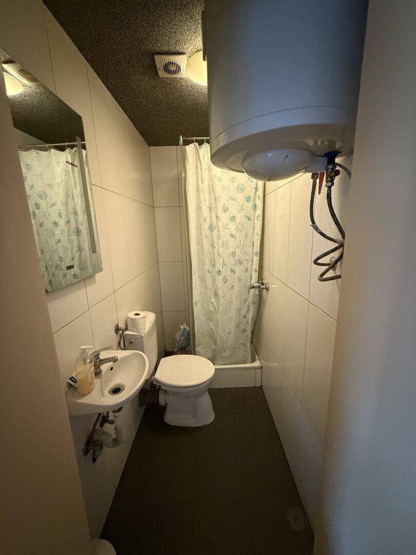 Kompaktes Badezimmer mit Dusche, WC und Waschbecken, ausgestattet mit weißen Fliesen.
