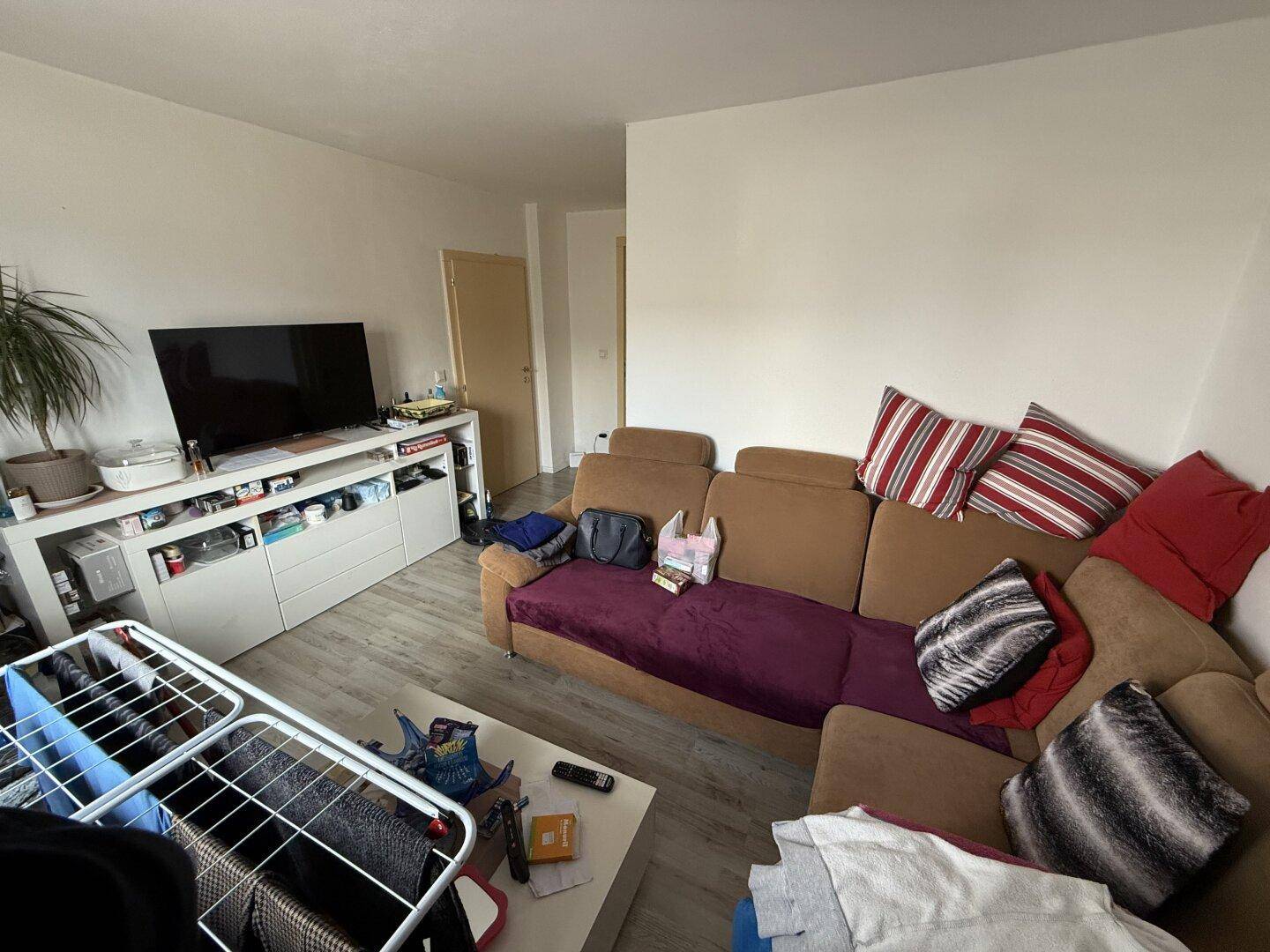 Wohnzimmer mit großem Ecksofa, TV-Möbeln und hellem Laminatboden.