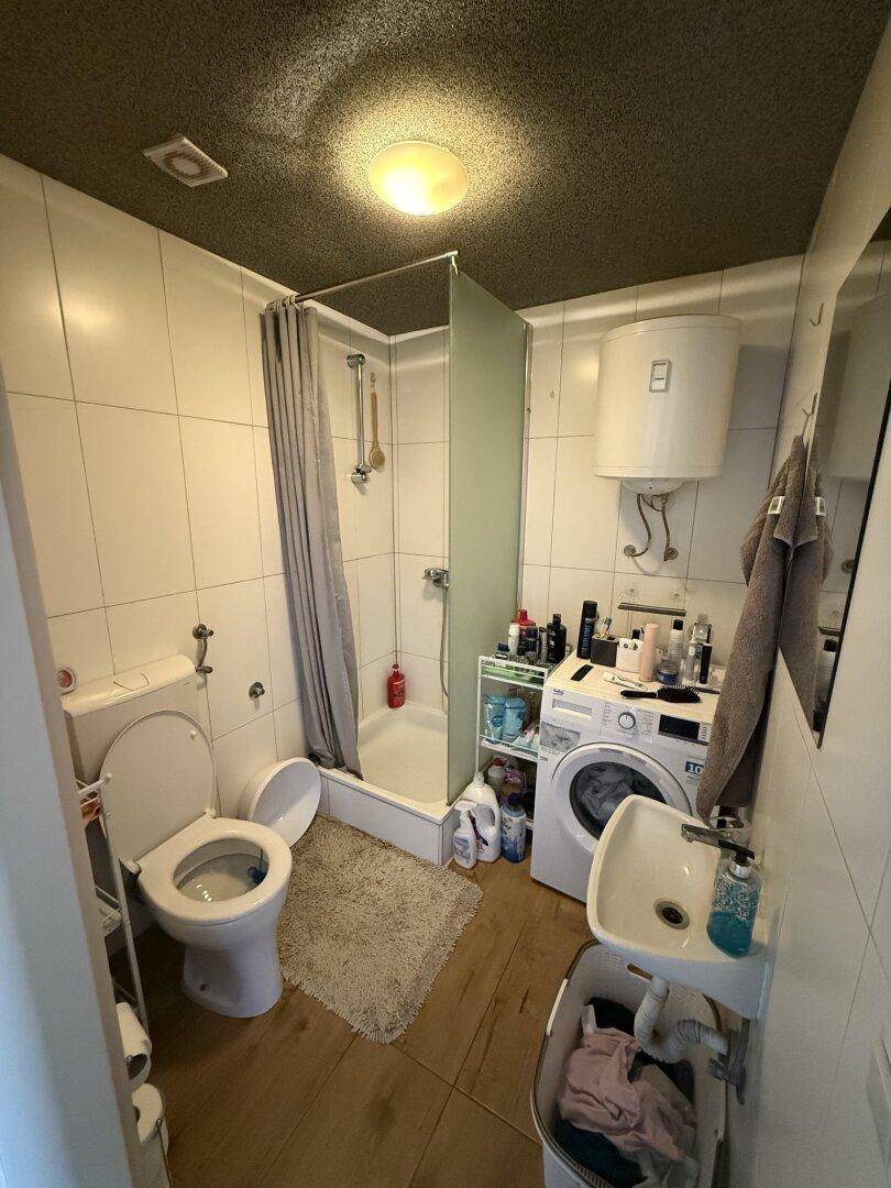 Badezimmer mit Duschkabine, Toilette, Waschbecken und einer Waschmaschine.