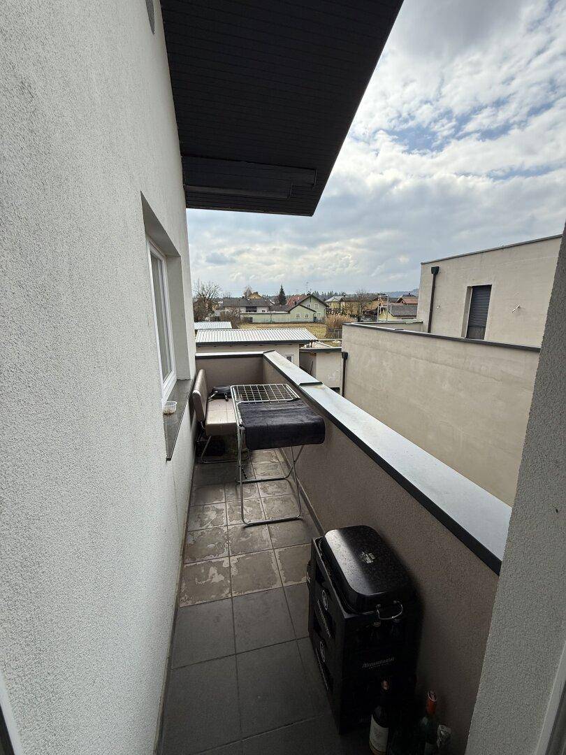 Schmaler Balkon mit Fliesenboden und einem Grill, ideal für kleine Outdoor-Mahlzeiten.