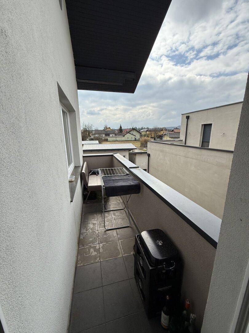 Kleiner Balkon mit Fliesenboden, Grill und Wäscheständer, mit Blick auf die Umgebung.