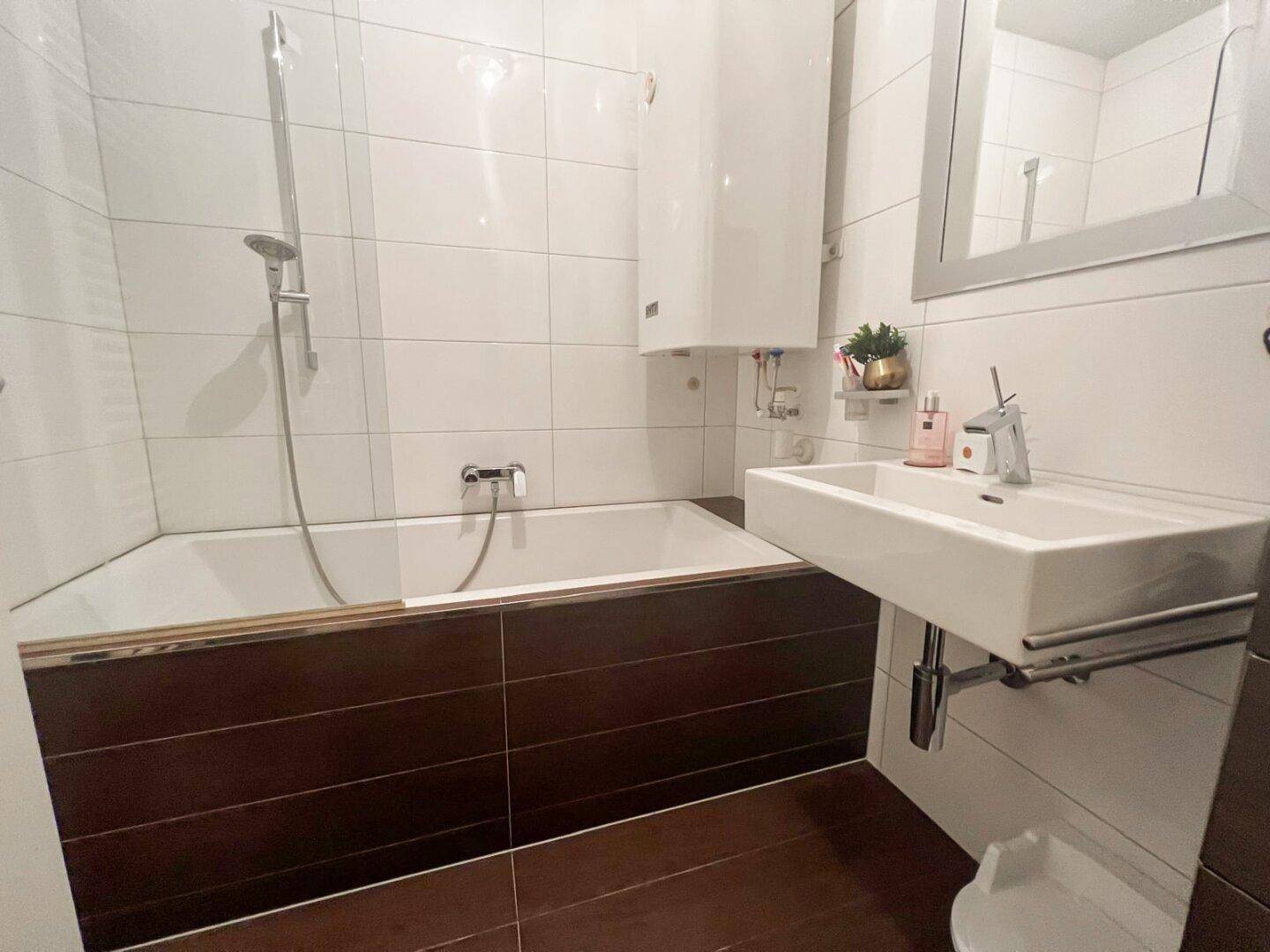 Funktionales Badezimmer mit Badewanne, Duschfunktion und modernem Waschbecken.