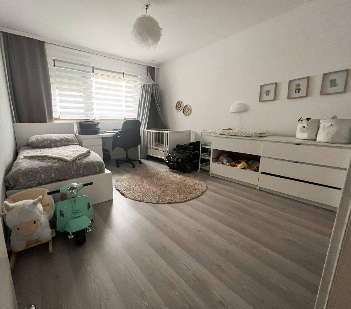 Helles Kinderzimmer mit Einzelbett, Babybett und Wickeltisch, ideal für Familien.