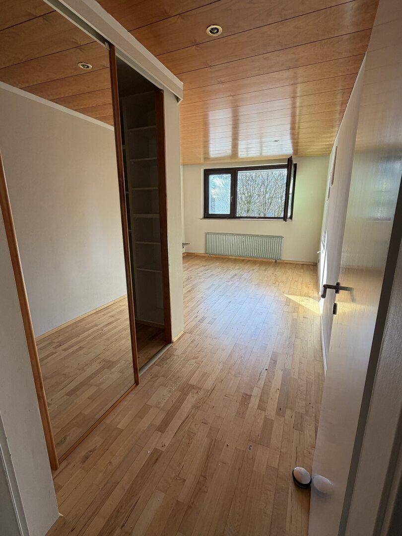 Helles Schlafzimmer mit Holzfußboden, Holzdecke und integriertem Spiegelschrank.