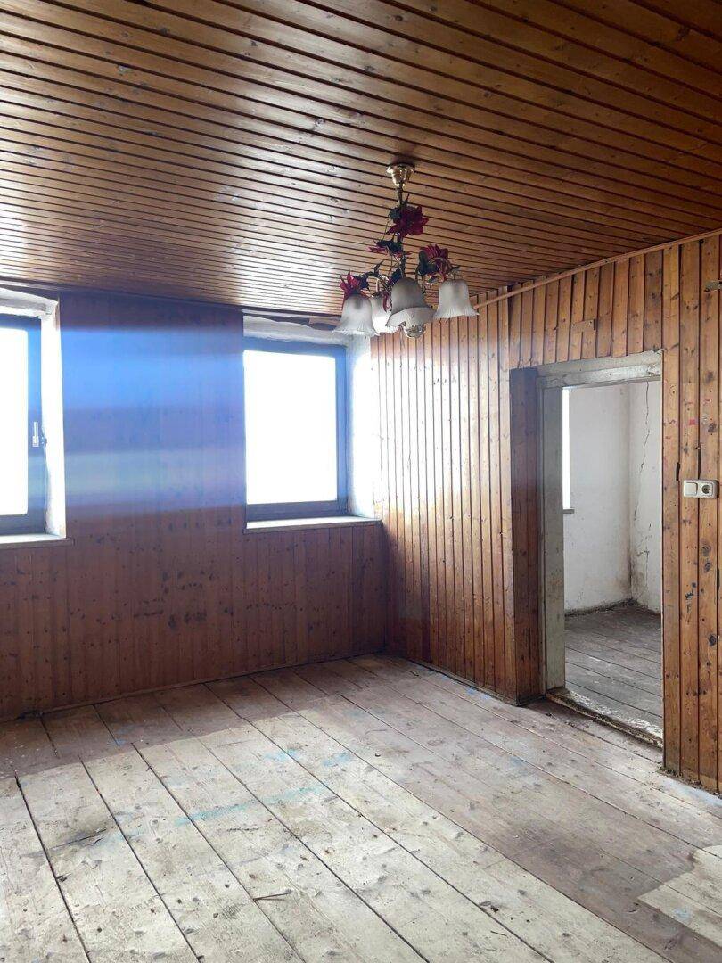 Geräumiger Innenraum mit Holzvertäfelung an Wänden und Decke sowie altem Dielenboden.