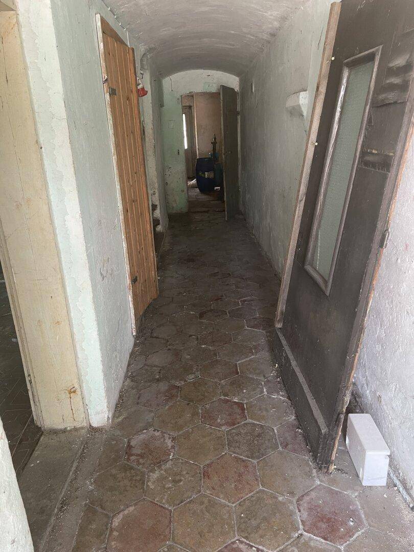 Langer Flur mit gewölbter Decke und sechseckigen Terrakotta-Fliesen auf dem Boden.