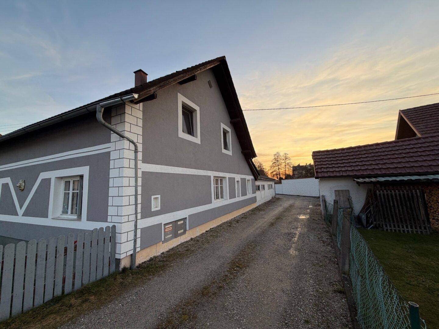 Seitenansicht des Hauses mit Kiesauffahrt und Blick auf die ländliche Umgebung.