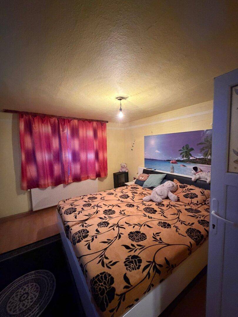 Schlafzimmer mit farbenfroher Dekoration, großem Bett und Vorhängen, gemütlich gestaltet.