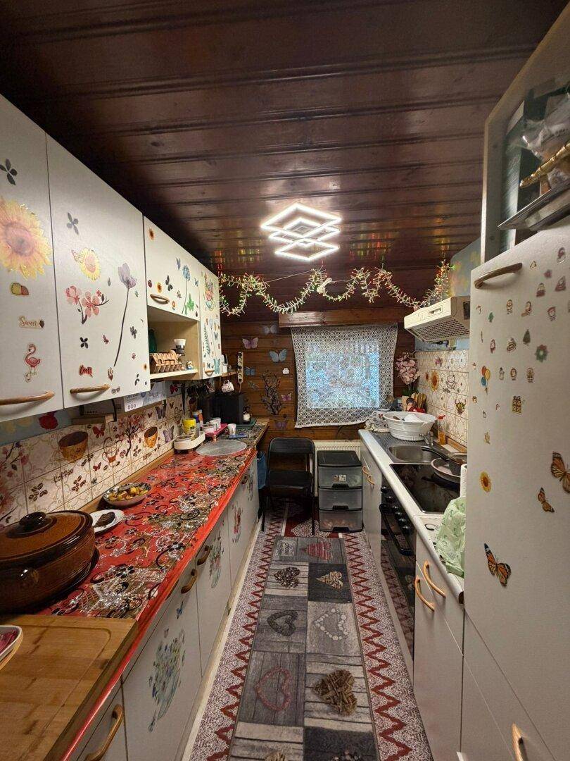 Detailansicht der schmalen Küche mit Holzdecke, bunten Schränken und Fenster.