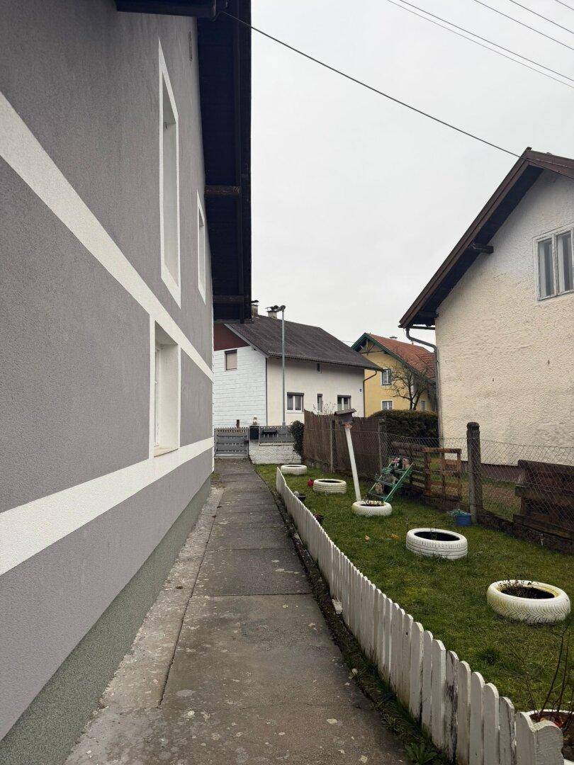 Seitenansicht des Hauses mit Gartenweg und angrenzendem Rasenbereich.