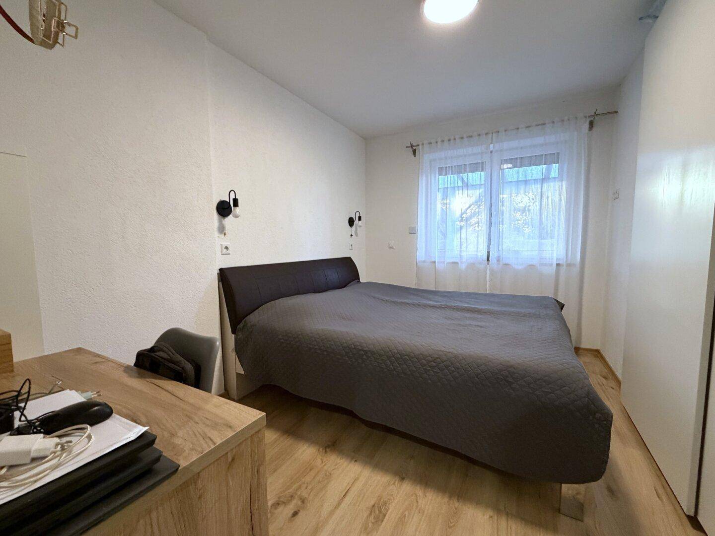 Gemütliches Schlafzimmer mit Holzboden, Doppelbett und weißem Kleiderschrank.