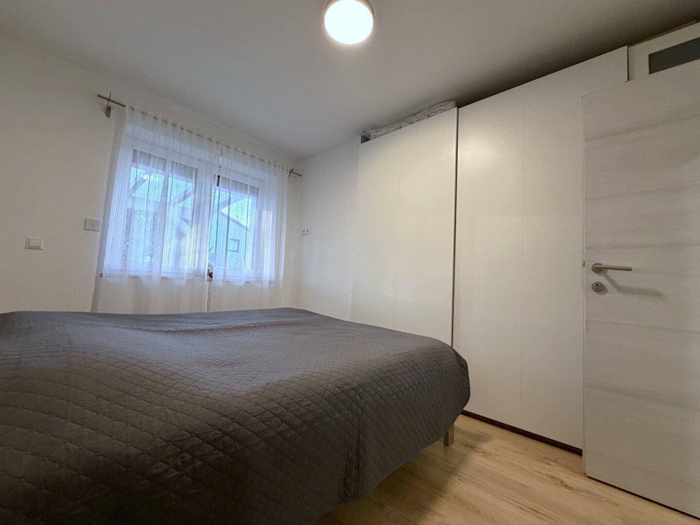 Schlafzimmer mit Holzboden, Doppelbett und großem weißen Kleiderschrank.