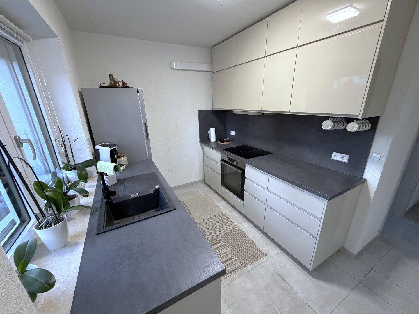 Funktionale Küche mit beigen Schränken, Induktionskochfeld und Backofen.