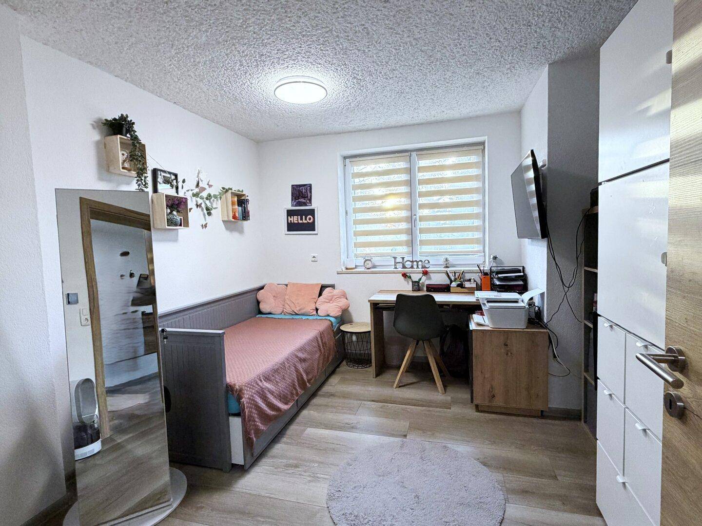 Kinderzimmer oder Arbeitszimmer mit Holzboden, Tagesbett und Schreibtisch am Fenster.