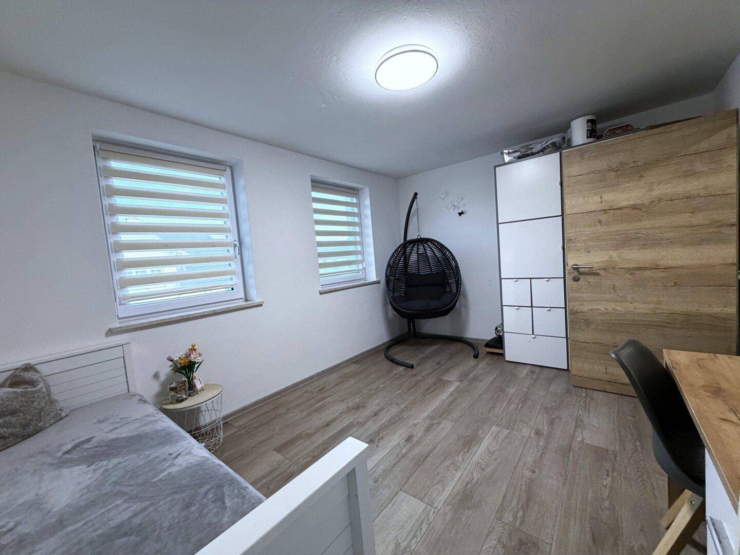 Geräumiges Zimmer mit Holzboden, Tagesbett und Schaukelstuhl.