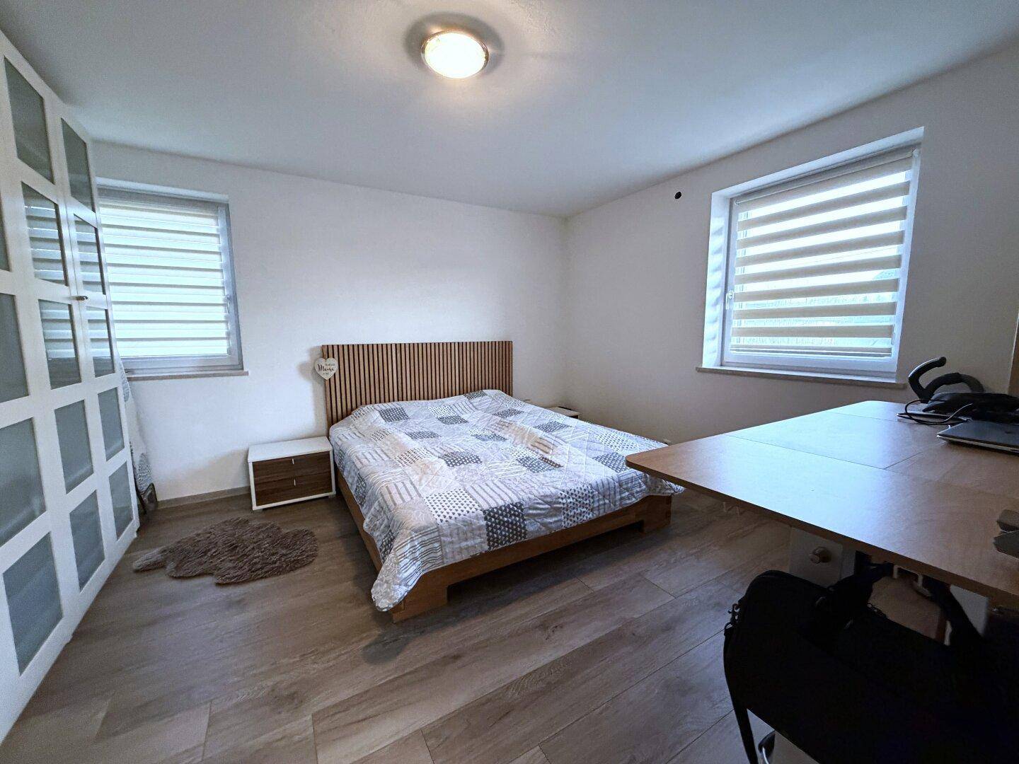 Schlafzimmer mit Holzboden, Doppelbett und großem Kleiderschrank.