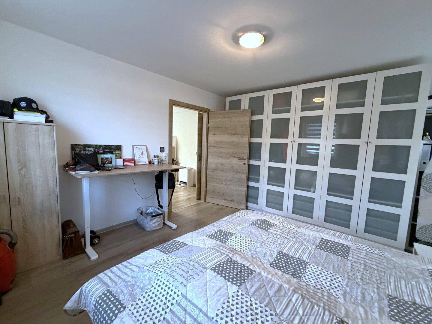 Helles Schlafzimmer mit Holzboden, Doppelbett und großem Kleiderschrank.