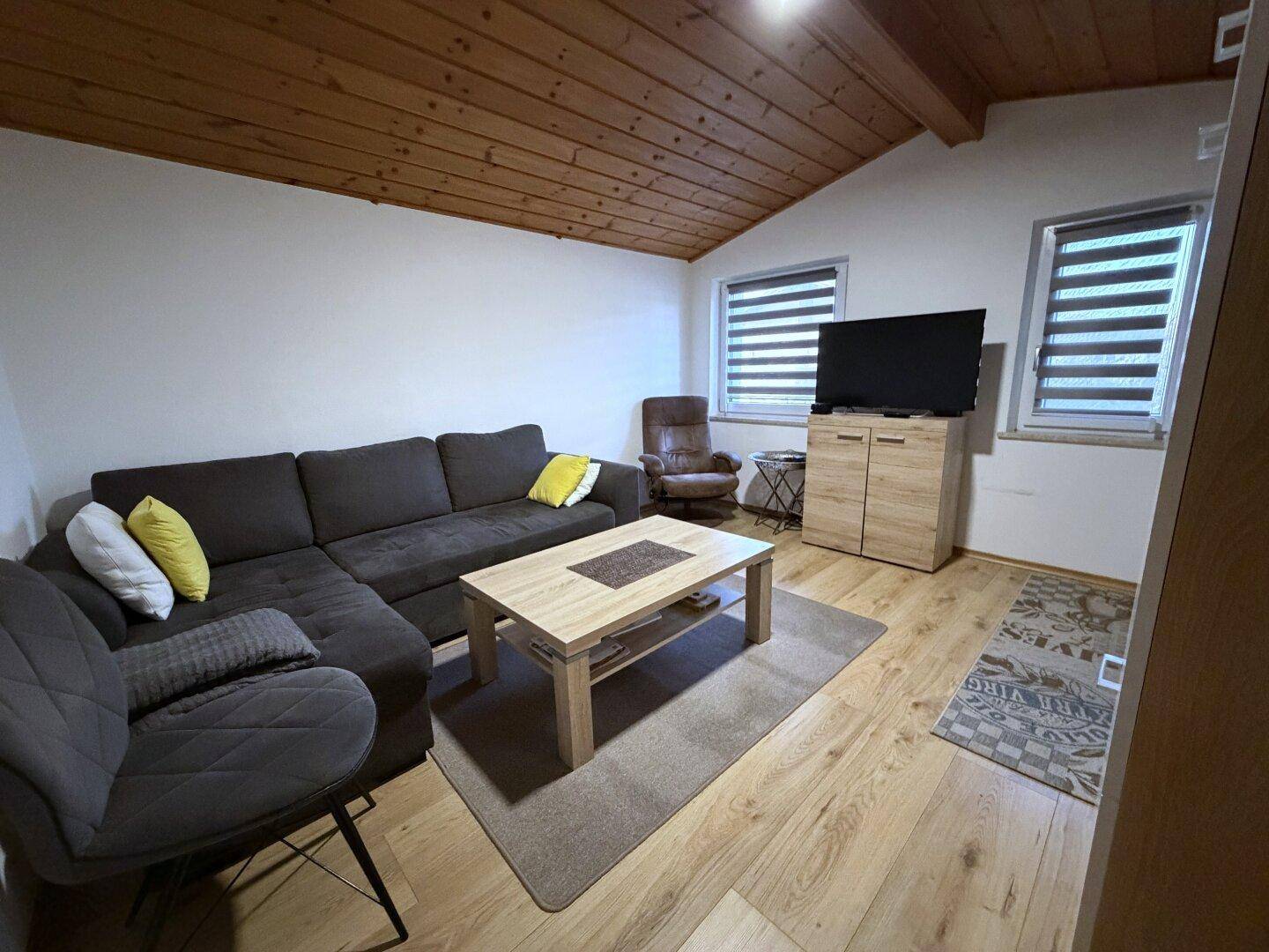 Wohnzimmer mit Holzboden, bequemer Couch und Holzdecke.