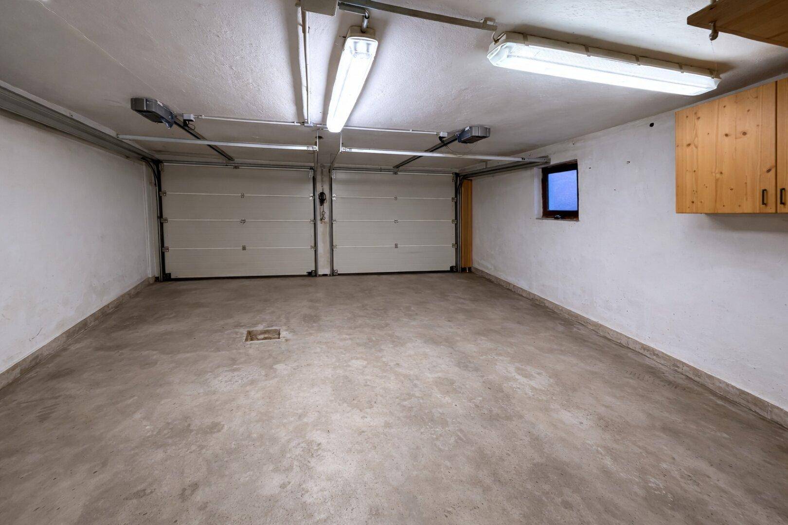 Geräumige Doppelgarage mit Betonboden und zwei Garagentoren.