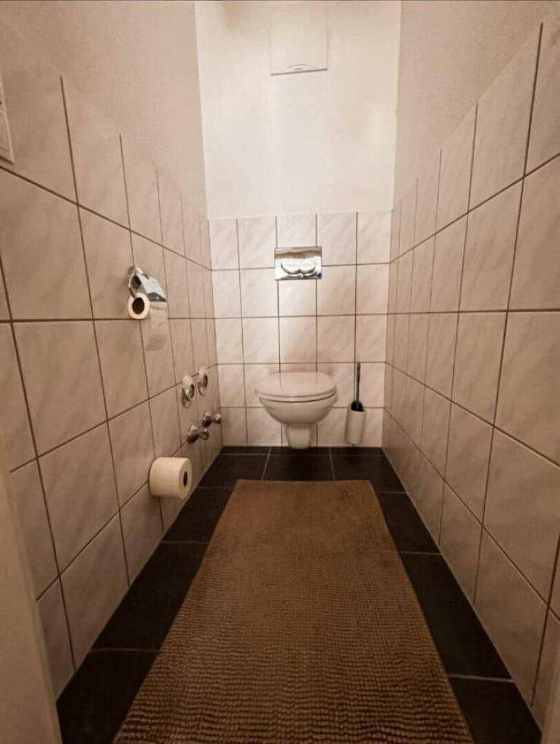 Modernes Gäste-WC mit Wand-WC und dunklen Bodenfliesen.