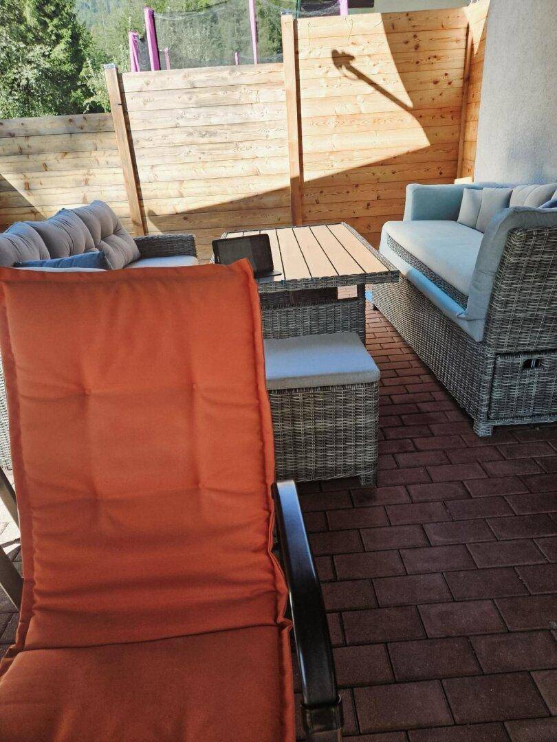Gemütliche Terrasse mit Rattanmöbeln und Holzsichtschutz für Privatsphäre.