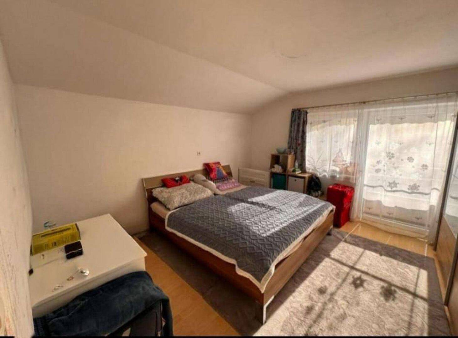 Schlafzimmer mit Doppelbett, Teppichboden und Zugang zu einem Balkon.